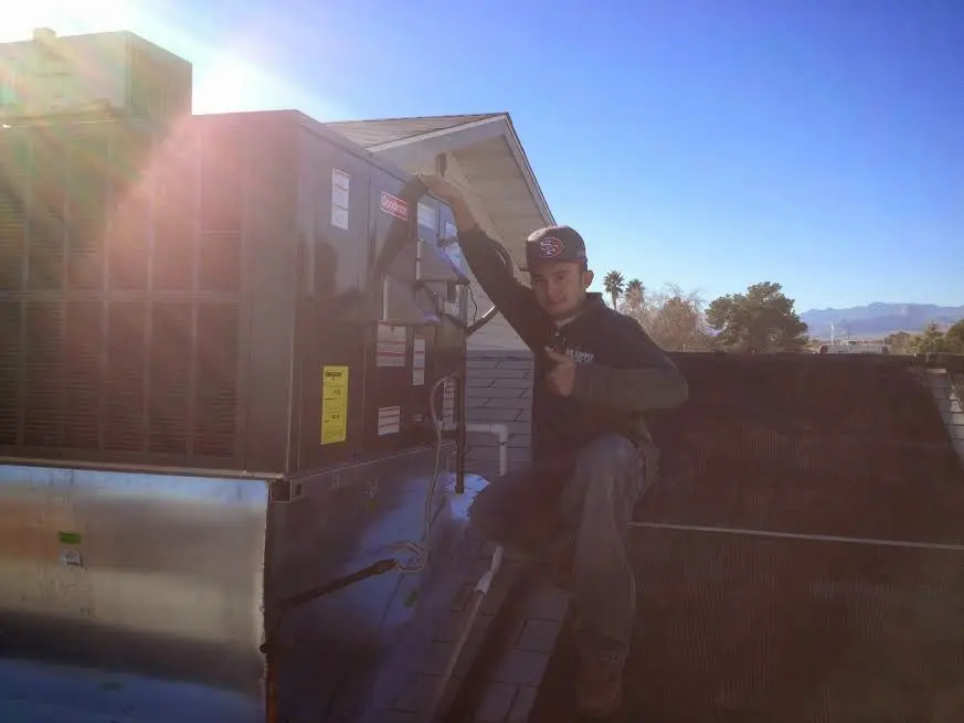 HVAC technician performing Air Duct Cleaning on a rooftop unit in Perry
